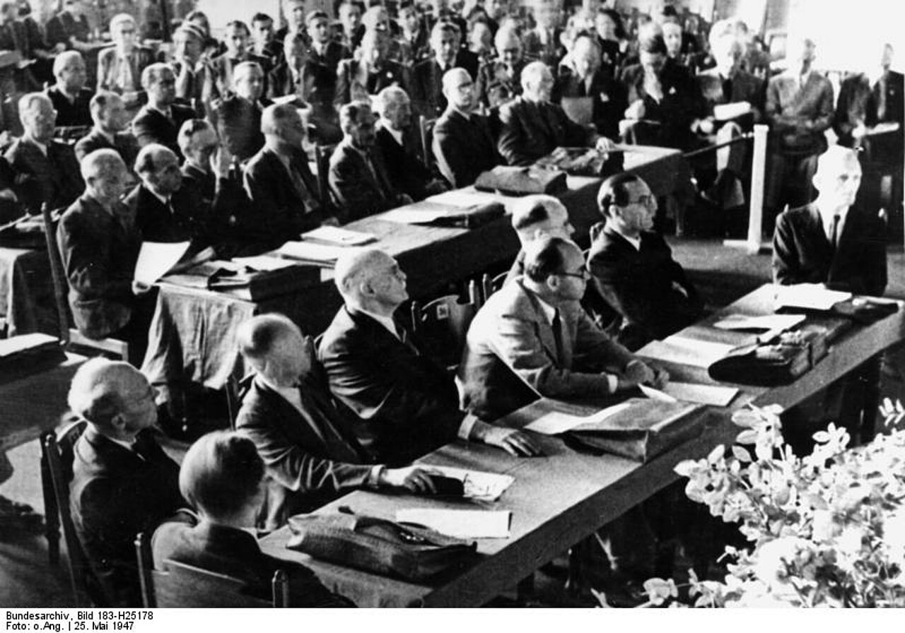 Bundesarchiv, Bild 183-H25178 / CC-BY-SA 3.0, via Wikimedia Commons <https://commons.wikimedia.org/wiki/File:Bundesarchiv_Bild_183-H25178,_Er%C3%B6ffnungssitzung_des_bizonalen_Wirtschaftsrates.jpg>